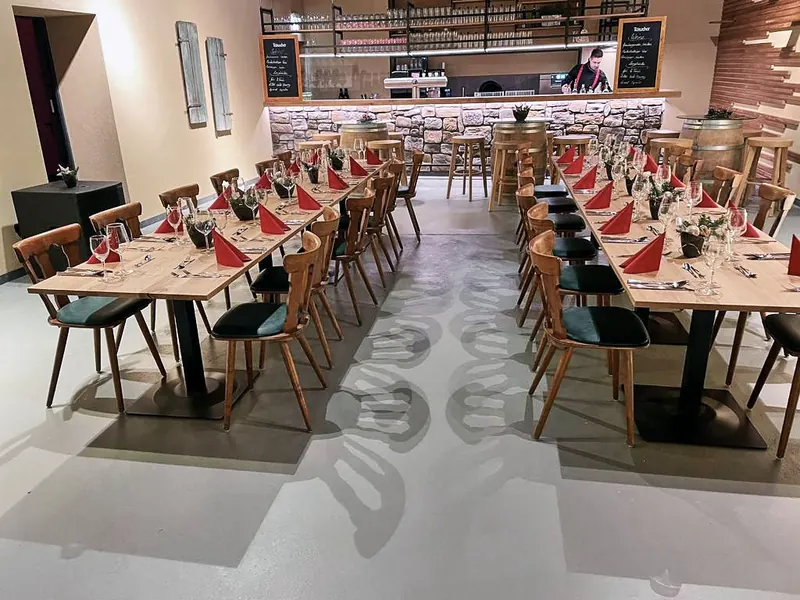 Weiter Blick durch den Saal auf Tafeln und Barhocker